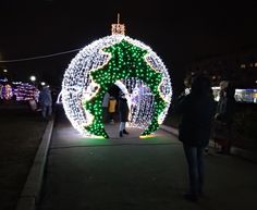 people are standing in front of a lighted christmas ornament