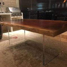 a wooden table sitting in the middle of a kitchen next to a stove top oven