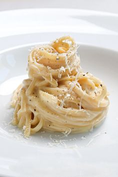 a white plate topped with pasta covered in cheese