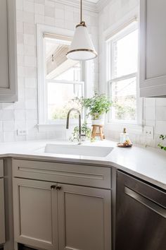 a kitchen with white walls and cabinets, an island sink and a dishwasher