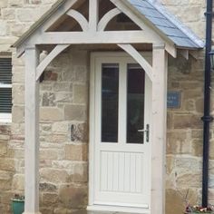 a white door with a blue roof on a stone building next to potted plants