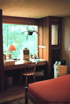 a bedroom with a bed, desk and lamp in it next to a large window