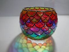 a colorful glass vase sitting on top of a white table next to a rainbow light