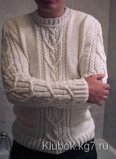 a man wearing a white sweater and black pants standing in front of a bathtub