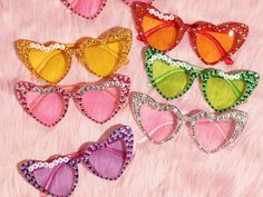 four pairs of colorful sunglasses with sequins and bows on pink furnishing