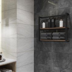 a bathroom with grey tiles and white towels on the shelf next to the bathtub