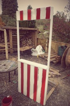 a red and white striped mirror sitting on top of a wooden table next to a pile of wood