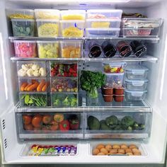 an open refrigerator filled with lots of different types of vegetables and fruits in plastic containers