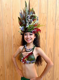 a woman in a green skirt and headdress standing next to a wooden wall