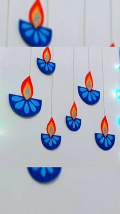 some blue and red candles hanging from strings with lights on them in the shape of flowers