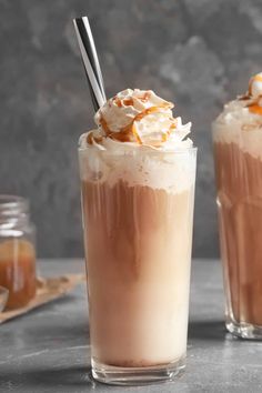 two glasses filled with ice cream and caramel on top of a table next to each other