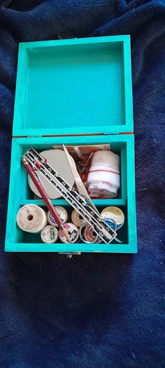 an open blue box filled with different types of sewing thread and other crafting supplies