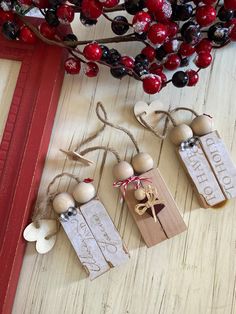 three wooden tags hanging from a red frame next to a tree with berries on it