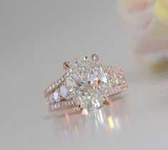 an oval cut diamond ring sits on top of a flower