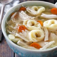 a bowl of chicken noodle soup on a wooden table