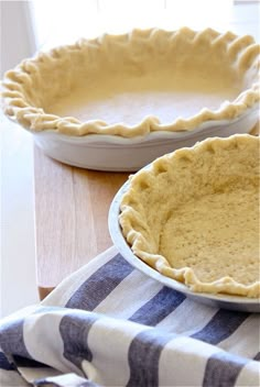 two pie pans sitting on top of a table next to each other, one with a pie crust in it