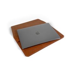 an apple laptop sitting on top of a brown leather case