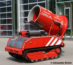 a large red machine is parked in front of a building