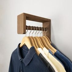 a wooden rack with clothes hanging from it's sides and two shirts on hangers