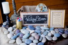 a table topped with rocks and candles next to a wooden sign that says wishing stones