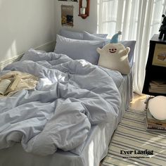 an unmade bed with blue sheets and pillows