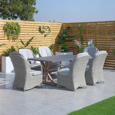 an outdoor dining table and chairs in the middle of a patio with a wooden fence behind it