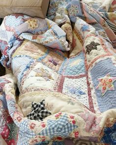 an unmade bed with many different colored quilts on it and a pillow in the middle