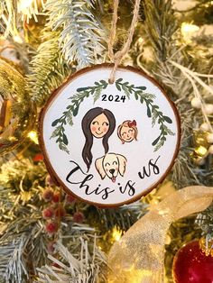 a christmas ornament hanging on a tree with ornaments around it and the words, this is us