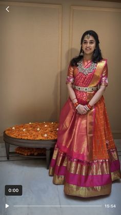 a woman in a red and gold dress standing next to a table