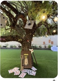 a tree that has some cards on it and lights hanging from the branches in front of it