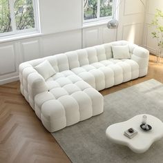 a large white couch sitting on top of a wooden floor next to a coffee table