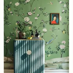 a green wall with flowers and birds painted on the walls next to a blue cabinet