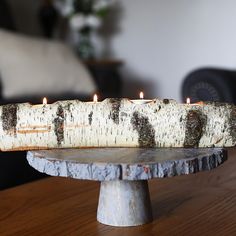 a wooden candle holder with four lit candles in it sitting on a table next to a couch