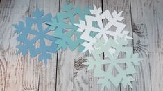 snowflakes cut out of paper sitting on top of a wooden table