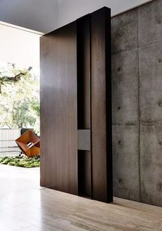 an open door in the middle of a room with wood flooring and concrete walls