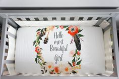 a baby crib with a white sheet and floral wreath on it that says, hello nest beautiful girl