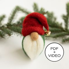 a small christmas ornament with a red hat on it's head is hanging from a pine tree