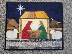 a quilted nativity scene with the birth of jesus and baby jesus in a manger