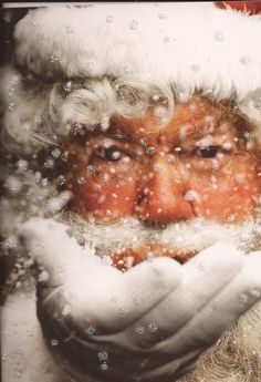 a santa clause holding his face in front of the camera with snow on it's hands