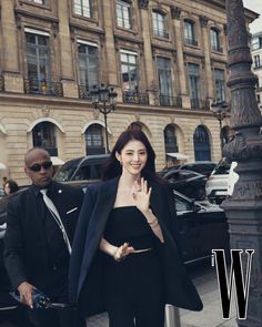 a woman standing next to a man in front of a tall building with the word w on it