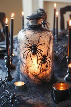 a table topped with candles and a jar filled with spider webs on top of it