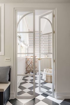 an entryway with black and white checkered flooring, arched glass doors leading into the dining room