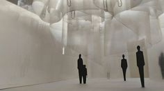 three people are standing in front of an art installation with white fabric hanging from the ceiling