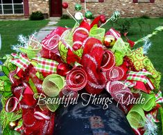 a red and green christmas wreath on top of a mailbox in front of a house