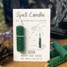 a green candle sitting on top of a table next to some cones and pine cones