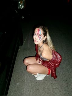 a woman sitting on the ground with her face painted