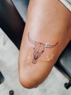 a woman's leg with a cow skull tattoo on it