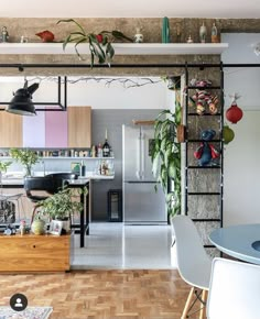 an open kitchen and dining area with wooden flooring, metal shelving, potted plants on the wall