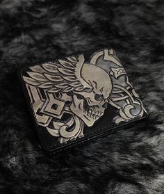 a wallet with a skull and cross on it sitting on top of a fur covered surface