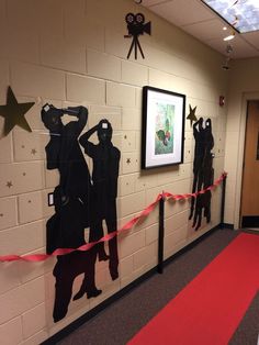 a hallway decorated with black paper cutouts and red carpeted flooring, two framed pictures on the wall